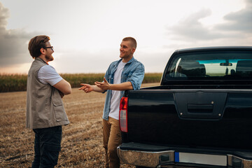 Two men standing in the field and talking.
