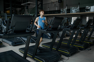 Fototapeta na wymiar Teenager boy running exercising on treadmill machine at sports gym