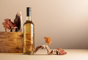 Bottle of white wine with a composition of old plank, dry snags, and dried vine leaves.
