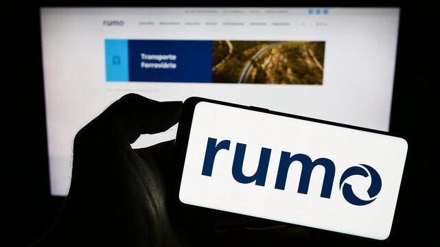 Stuttgart, Germany - 08-26-2023: Person holding cellphone with logo of Brazilian logistics company Rumo S.A. on screen in front of business webpage. Focus on phone display.