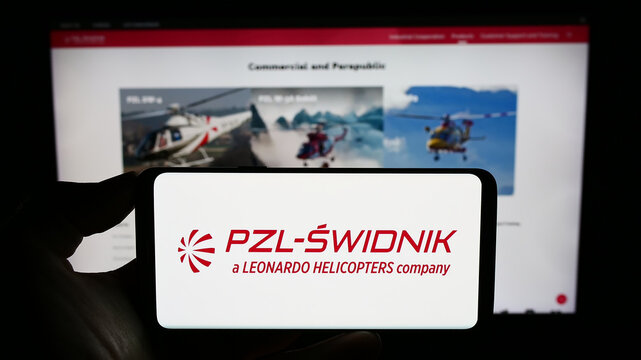 Stuttgart, Germany - 08-26-2023: Person holding cellphone with logo of Polish defence company PZL-Swidnik S.A. on screen in front of business webpage. Focus on phone display.