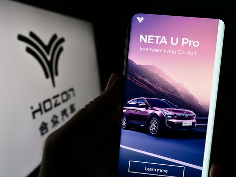 Stuttgart, Germany - 08-28-2023: Person holding smartphone with website of Hozon Auto New Energy Automobile Co. Ltd. on screen in front of logo. Focus on center of phone display.