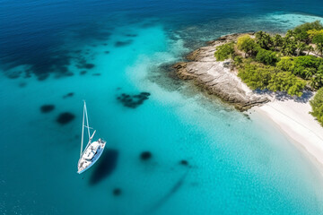 Aerial view of beautiful white sand beach with crystal clear turquoise water and yacht