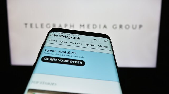 Stuttgart, Germany - 08-28-2023: Smartphone with website of company Telegraph Media Group Limited (TMG) on screen in front of business logo. Focus on top-left of phone display.