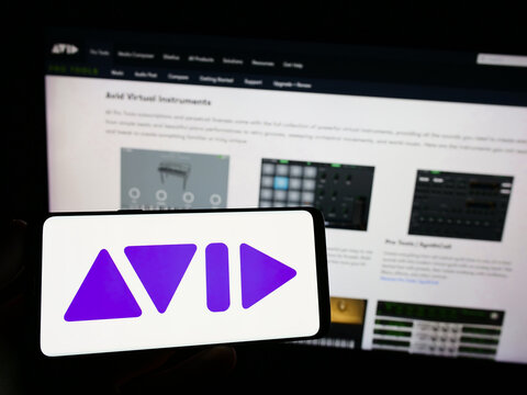 Stuttgart, Germany - 08-29-2023: Person holding mobile phone with logo of American software company Avid Technology Inc. on screen in front of web page. Focus on phone display.