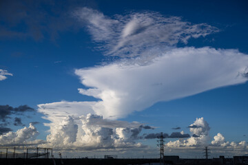 夏空のもと、鉄塔が立ち並ぶ地平線に湧き上がる積乱雲