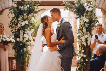 Bride and groom first kiss at altar at wedding. Happy couple excited smile for wedding, happiness and marriage. Generative AI