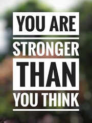 Motivational quote "You are stronger than you think" on blurred nature background.