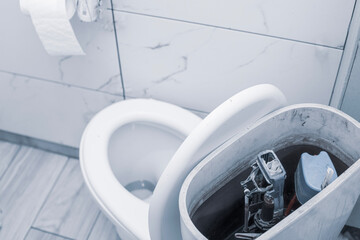 ceramic old white toilet while repairing a flush device close-up, the background is blurred with a bokeh effect