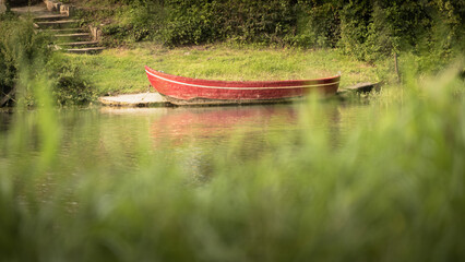Bateau rouge sur le lac avec de l'herbe verte en arrière-plan. Mise au point sélective.