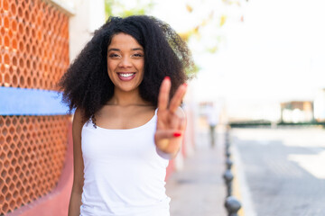 Young African American woman at outdoors smiling and showing victory sign