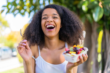 Young African American woman holding a bowl of fruit at outdoors