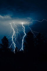 beautiful lightning during a thunderstorm at night in a forest that caused a fire, against a dark...