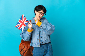 Woman holding an United Kingdom flag over isolated background celebrating a victory