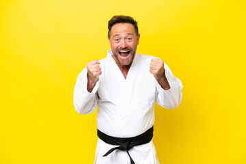 Middle age caucasian man doing karate isolated on yellow background celebrating a victory in winner...
