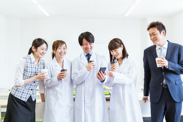 休憩でスマホを見る病院で働く医療従事者の男女（オンライン診療・スマホ診・遠隔診療）
