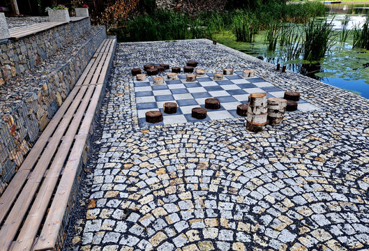 recreation terrace in the park on the waterfront. the tiles in the checkerboard pattern and the blocks represent the game pieces of checkers. drafts table game. large scale. granite paving. ludo