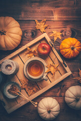 Autumn mood concept. Warm, cozy and rustic still life with cup of tea, candle and pumpkins.