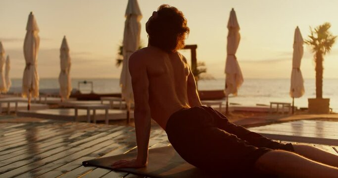 Review of a guy who took a special pose during a yoga class and meditates on a sunny beach in the morning