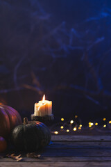 Fototapeta premium Vertical image of pumpkins and candle with copy space on dark background
