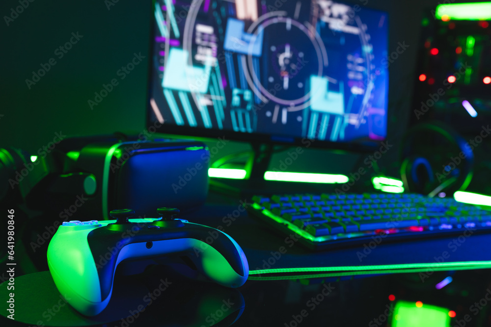 Poster composite of computer, keyboard with video game accessories with copy space on neon background