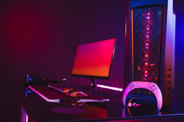 Composite of computer with video game accessories with copy space on neon background