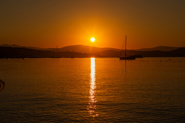 Fototapeta na wymiar beautiful sunrise over Bodrum. clear sky and orange sun. boats sailiing on the sea
