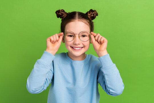 Portrait of funny small girl try on eyesight specs eyeglasses oculist examination checkup isolated green color background