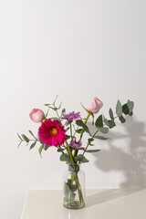 Vertical image of pink flowers in glass vase and copy space on white background