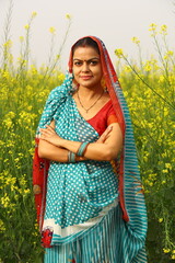 Happy rural Indian women standing in a mustard field enjoying the benefits of the mustard agricultural field.