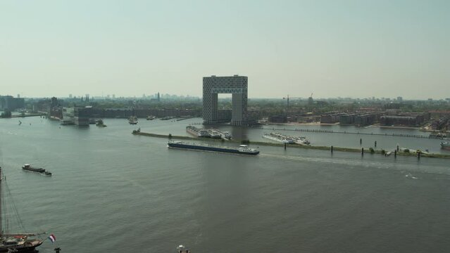 Barge Cruising In The IJ River Passing By Hotel Pontsteiger In Amsterdam, Netherlands. - aerial
