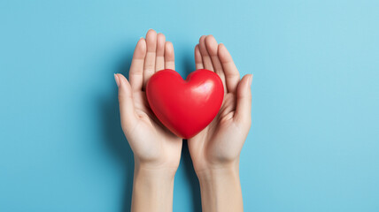 woman hand with red heart in studio on blue background.