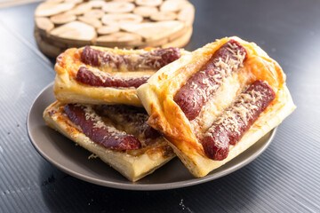puff pastry with sausage on a black background. diet. food concept.mini pizza.
