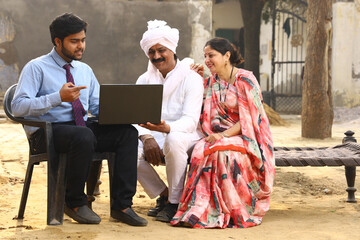 Happy rural Indian family in village Aspirational family sitting with a insurance agent showcasing...