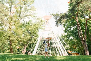 Mom throws her son in the summer park. Family pastime. The happiness of childhood and motherhood.