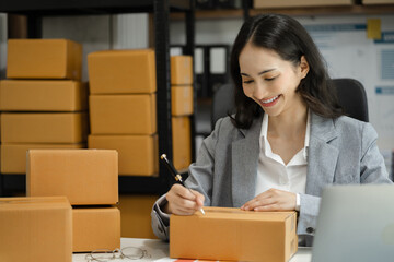 Shipping shopping online ,woman start up small business owner writing address on cardboard box at...