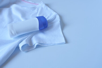 White t-shirt with antiperspirant on blue background. The concept of an anti-sweat odor product.