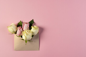 Naklejka premium White and pink rose flowers in brown envelope and copy space on pink background