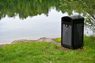 Garbage bin of metal near small lake in Kumla Sweden