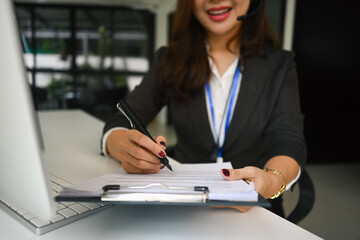 Smiling female customer support operator with headset working on support hotline in modern office