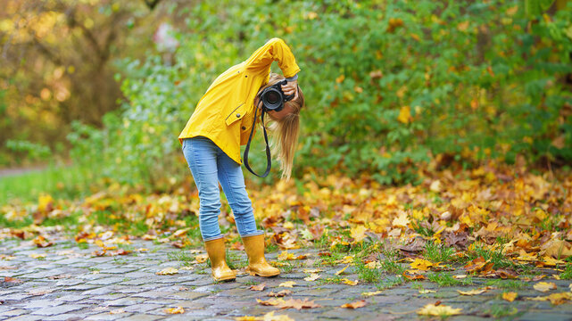 Happy photographer girl, little child, kid taking a picture with professional camera in nature