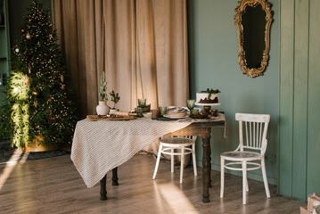 Beautifully decorated and served dining christmas table in the living room in a Scandinavian-style house in green