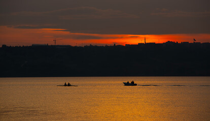 Silhouettes of people rowing at sunset in the lake located in Istanbul Province, Büyükçemece District