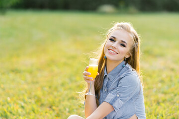 Young happy woman holds a glass of orange juice in her hand