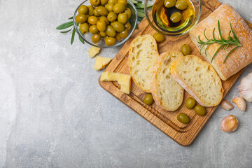 Ciabatta and olives. Fresh italian ciabatta bread with herbs, olive oil,parmesan and pesto sauce, olives on wooden background, top view, copy space.Flatley. Place for text. copy space.