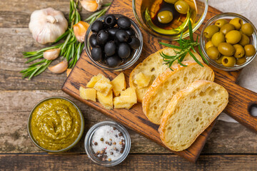 Ciabatta and olives. Fresh italian ciabatta bread with herbs, olive oil,parmesan and pesto sauce, olives on wooden background, top view, copy space.Flatley. Place for text. copy space.
