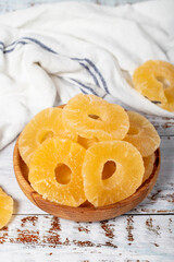 Natural dried pineapple slices in bowl on wooden background. Fruit snack for a health diet and alternative desert. Close up