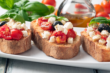 Deliziose bruschette mediterranee alla caprese, bruschette con pomodoro, mozzarella, basilico, olive nere, olio di oliva e origano, cibo italiano 