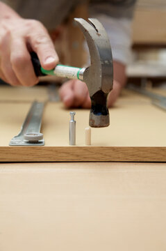 Close up of man's hands with hammer and flat pack detail
