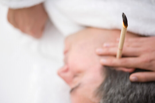 Close up of man's head with burning ear candle
